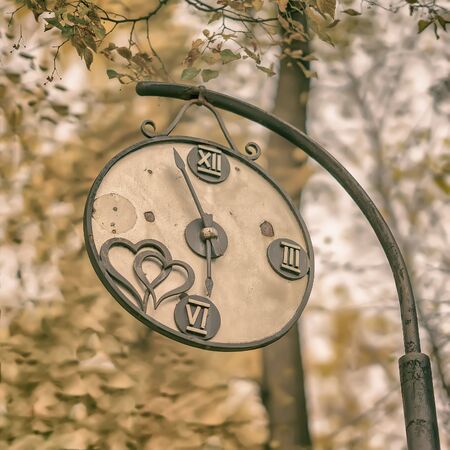 Close-up of broken decorative vintage watch in an old park. Concept of change of seasons, Autumn nostalgic mood, melancholy.の写真素材