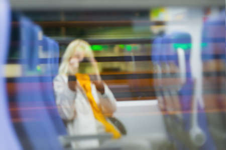 Abstract defocused image of unrecognizable silhouettes of young women sitting in train by window and photographing, night. Blur effectの写真素材
