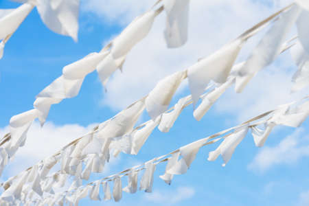 White flags of triangular shape, pennants against blue sky in diagonal garland. City street holiday, Festival, marine theme, celebration conceptの写真素材