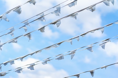 Diagonal garland of white flags of triangular shape, pennants against blue cloudy sky. City street holiday, Festival, marine theme, celebration conceptの写真素材
