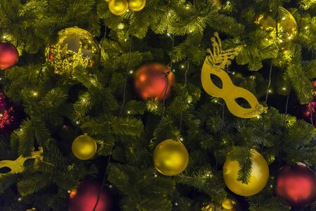 Golden carnival mask and colorful bright shiny celluloid balls on Christmas tree. Festive occasions concept, holiday, Christmas, New Year backdropの写真素材