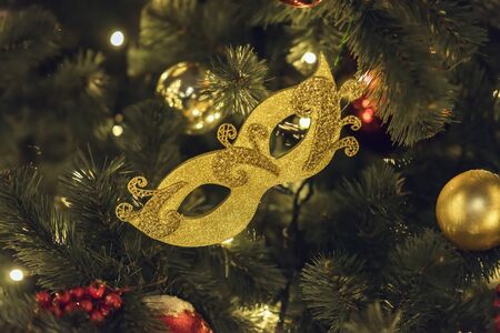 Golden carnival mask and bright shiny celluloid balls on Christmas tree. Festive occasions concept, holiday, Christmas, New Year backdropの写真素材