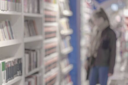 Unrecognizable Girl in bookstore. Many of interesting books. Education, school, study, reading fiction concept. Light backgroundの写真素材