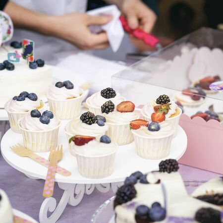 Different appetizing tartlets, cake basket with white cream and fresh multi-colored berries, summer...