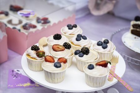 Different appetizing tartlets, cake basket with white cream and fresh multi-colored berries, Fresh summer dessert, selective focus with blueberries, blackberries, strawberriesの写真素材
