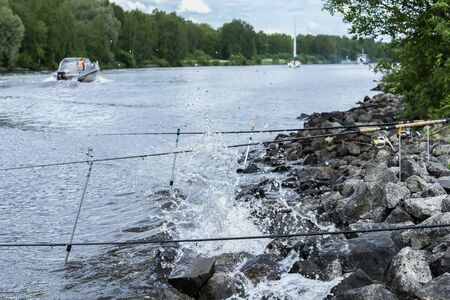 Summer landscape with fishing rods on background of lake, opposite shore, morning, Yacht, beach with stones. Seasons, ecology, ctive rest, hobby, countryside relaksの写真素材