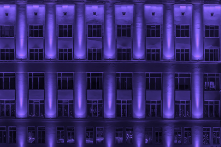 Architectural toned background of modern Iron-concrete wall with windows. Multistory buildings at night, Illuminated windows. Modern neon city, art texture imageの写真素材