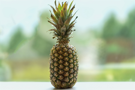 Ripe pineapple on white wooden table on abstract green background , tropic summer conceptの写真素材