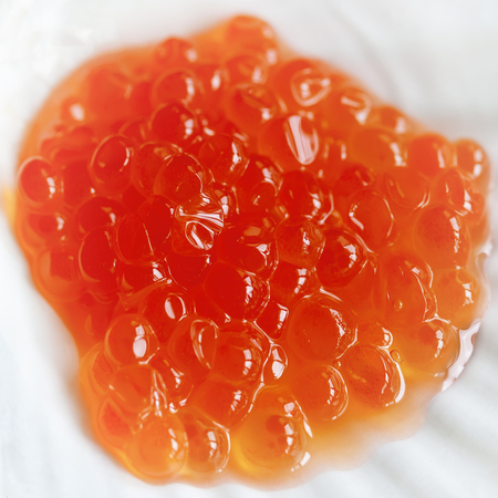 Red salmon caviar on a white board. Top view