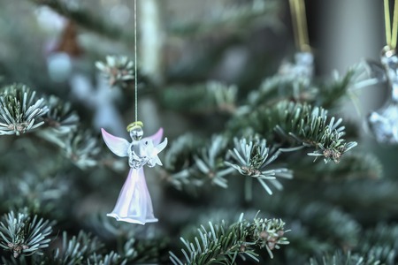 Figure of pink angel with dove in his hands on a branch of spruce, glass Christmas decoration, background with copy spaceの写真素材