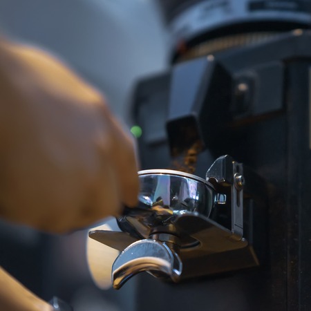 Professional grinding freshly roasted coffee in espresso machine. Barista preparing coffee in bar. Professional coffee making, service and catering conceptの写真素材