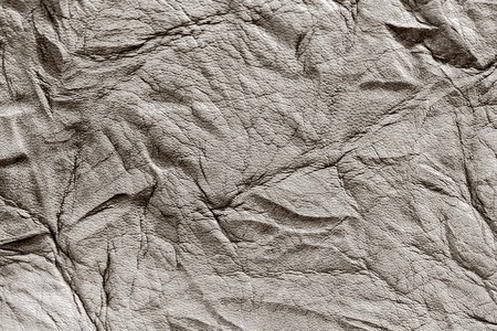 Texture of rough crumpled genuine leather close-up, with embossed wrinkles, matte surface, trendy backgroundの写真素材