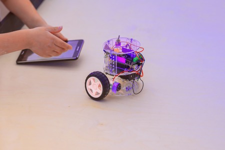 Assembled model of a computer all-terrain vehicle, robotic toy controlled with tablet in the hands of a childの写真素材