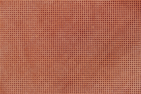 Texture of genuine geometric perforated leather close-up, painted orange brown color. For...