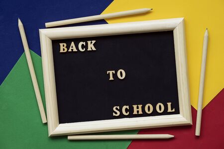 Back to school text and wooden pencils on black blackboard in wooden frame. Concept of education, starting school. Colorful backgroundの写真素材