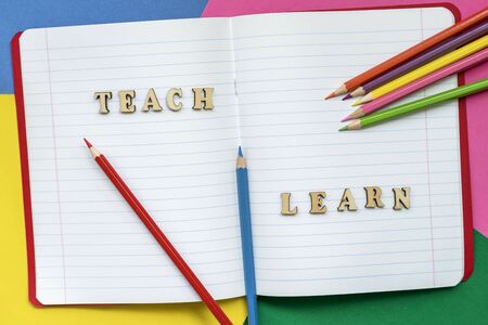 Teach and learn, words in open notebook, colorful crayons and colored paper sheets. Concept of education, starting schoolの写真素材
