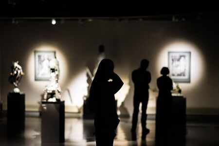 Silhouettes of unrecognizable people, visitors to an art gallery, a museum with paintings, selective focusの写真素材