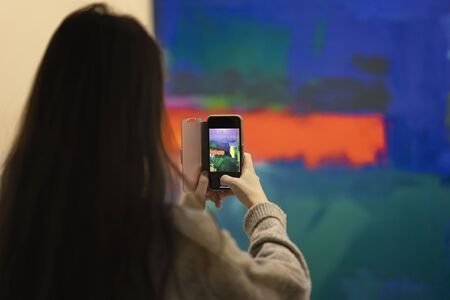 Smartphone in the hands of a girl making a bright background pictureの写真素材