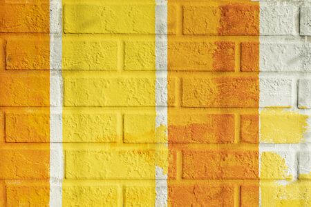 Bricks surface of wall, painted striped in bright orange and yellow colors. Graphic texture of colorful wall, for backgroundの写真素材