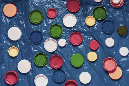 Mix of colorful plastic caps ready to be recycled, crumpled polyethylene. Concept of recycling, ecology, environmental pollutionの写真素材