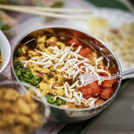 Asian food, spicy soup with vegetables, seafood and germinated soybean sprouts in a bowl close-up,...
