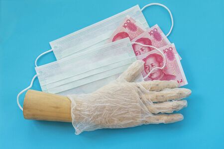 Wooden model of hand with disposable protective masks and cash chinese money. Concept of medicines...