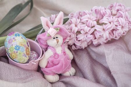 Easter rubbit in a natural bird's nest with chocolate Easter eggs next to e spring flower. Home Easter holiday compositionの写真素材