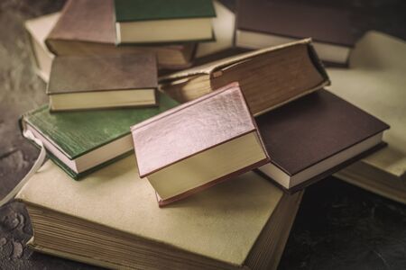Chaotic heap of books. Vintage still life. Concept of back to school, education, reading time. Dark...