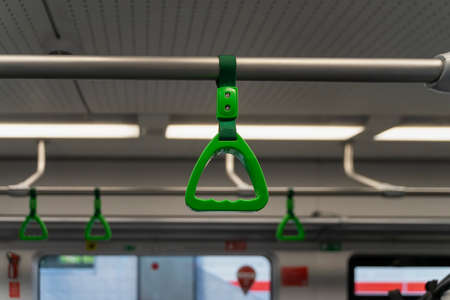 Abstract blurred background of subway train interior, selective focus of green handles for...