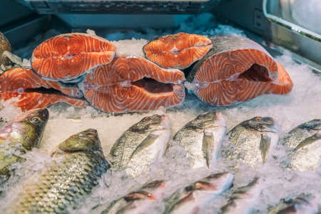 Sale of fresh frozen fish on farmer's bazaar. Open showcases of seafood market. Fish store. Pieces of salmon fresh salmon on ice in supermarket close-upの写真素材