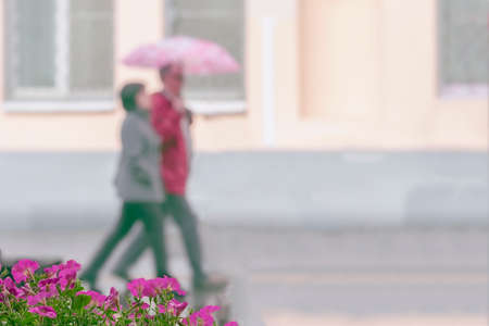 Walking happy couple together, city street in rainy day. Concept of modern city, love, lifestyle. Abstract blurred backgroundの写真素材