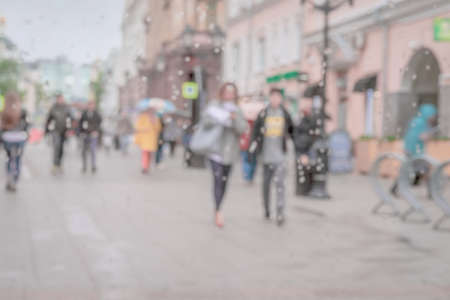 Young people walking down the street in rainy day. Raindrops on window glass. Concept of modern...