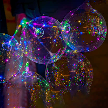 Colorful LED balloons on the black background. Multicolored vivid glowing bokeh lights at night.