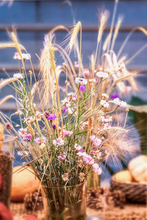 Autumn scenic bouquet of autumn wheat ears, field flowers, festive seasonal decor, selective backgroundの写真素材