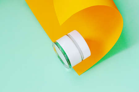 Cosmetic cream in glass jar on yellow green background of craft paper. Skin care conceptの写真素材