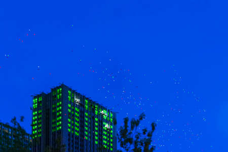 Multicoloured hot air balloons fly high in sky over city houses in summer. Night. Holiday conceptの写真素材