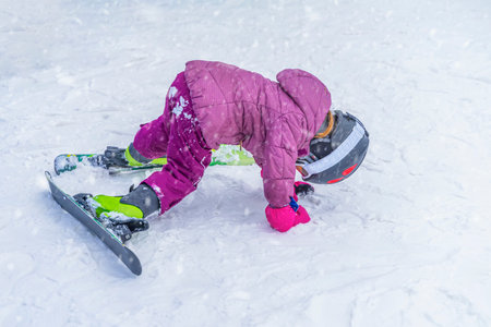 Winter, kid snowboarder on the ski slope in bright pink jacket. Winter holidays, sports and outdoor activitiesの写真素材