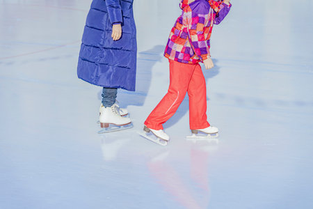 Abstract unrecognizable mother with daughter skating outdoors in skating rink. Winter activity, family sport conceptの写真素材