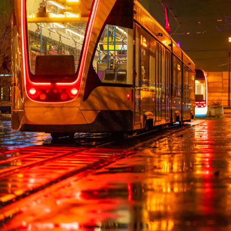 Abstract blurred background of tram on line at night close up, illuminated street, public transport stoppingの写真素材