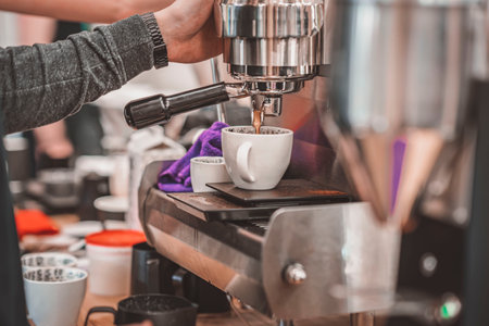 Hands of Professional barista making coffee in coffee shop, coffee machine pouring fresh drink into porcelain cupの写真素材