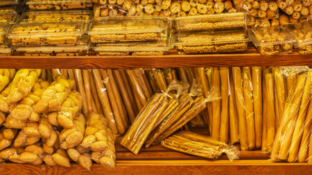 Variety of packaged breadsticks, pastries, and baked goods are neatly displayed on wooden shelves in...