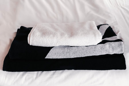 Soft towels neatly folded on a bedspread in a cozy bedroom, ready for use during a refreshing morning routine or spa dayの写真素材