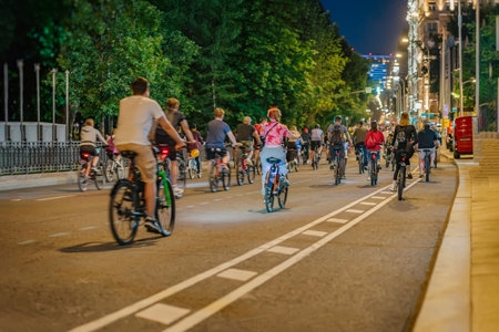 People cycling together at night along a city streetの写真素材