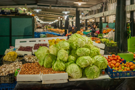 A market stall with a colorful variety of vegetables, cabbages, tomatoes, and garlicの写真素材