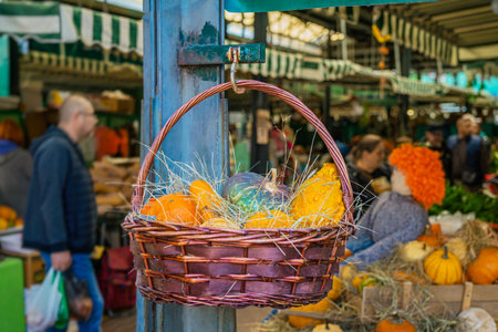 Wicker basket with colorful pumpkins, autumn harvest at a lively marketの写真素材