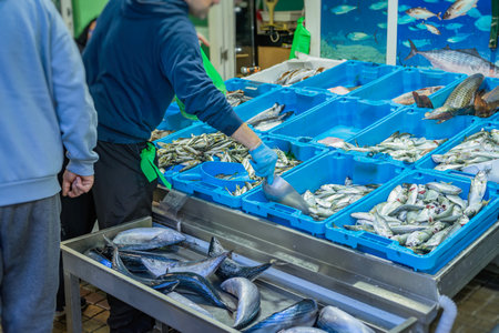 Busy fish market stall with vendor, fresh catch early in the morning in a coastal townの写真素材
