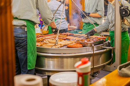 Large sausages grilling on an outdoor barbecue stand close up with vendors. Concept of traditional market foodの写真素材