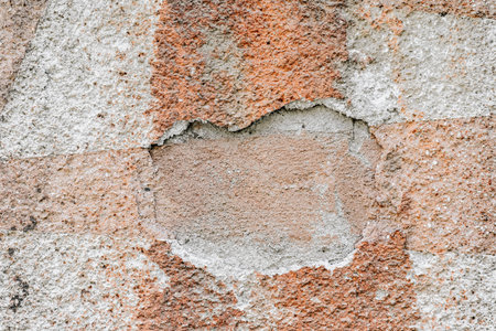 Texture of old painted brick wall with peeling paint. Old textured stucco wall with visible brick layer, eroded surface detail. Concept of history, aging, vintage architectural background, copy spaceの写真素材