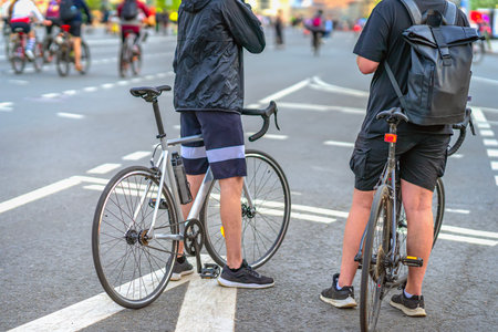 Cyclists. Two men in sportswear standing with bicycles on wide city street during urban cycling...