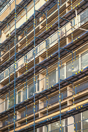 Scaffolding structure on building facade during renovation with geometric metal patterns. Concept of...